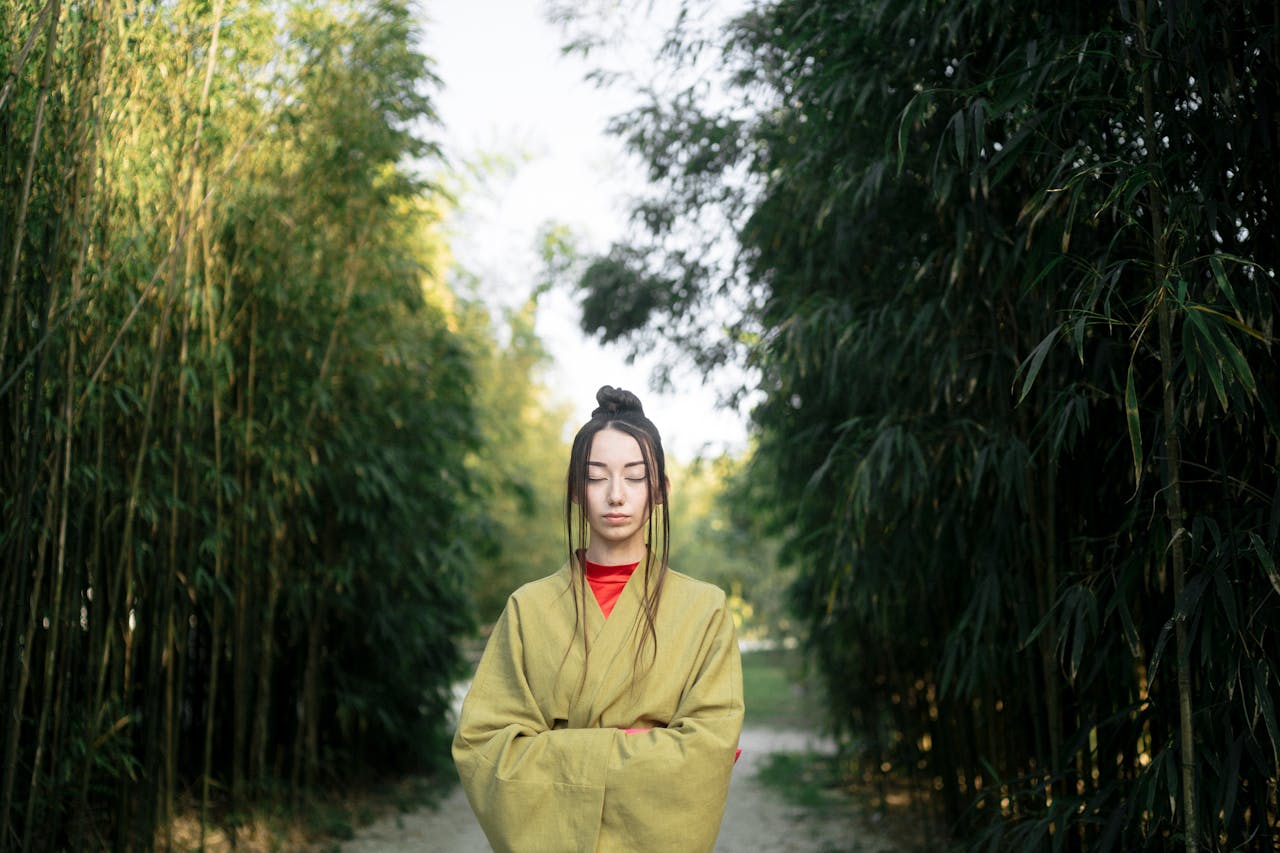 A woman in a kimono meditates in a tranquil bamboo garden, embracing Japanese aesthetics.